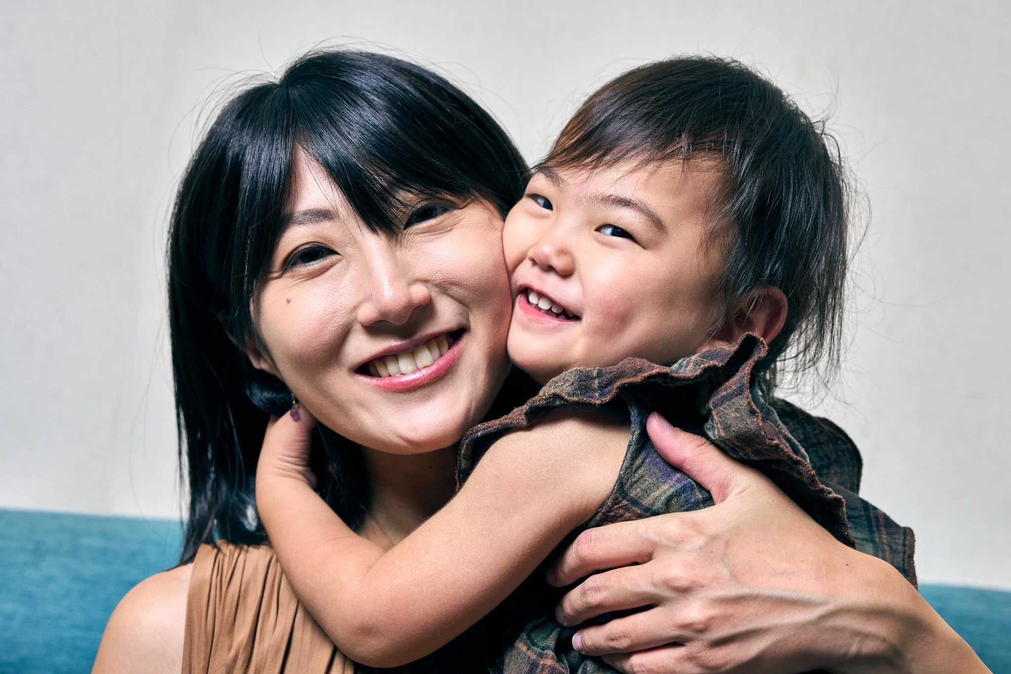 母親と子どもが頬を寄せて笑い合う家族写真