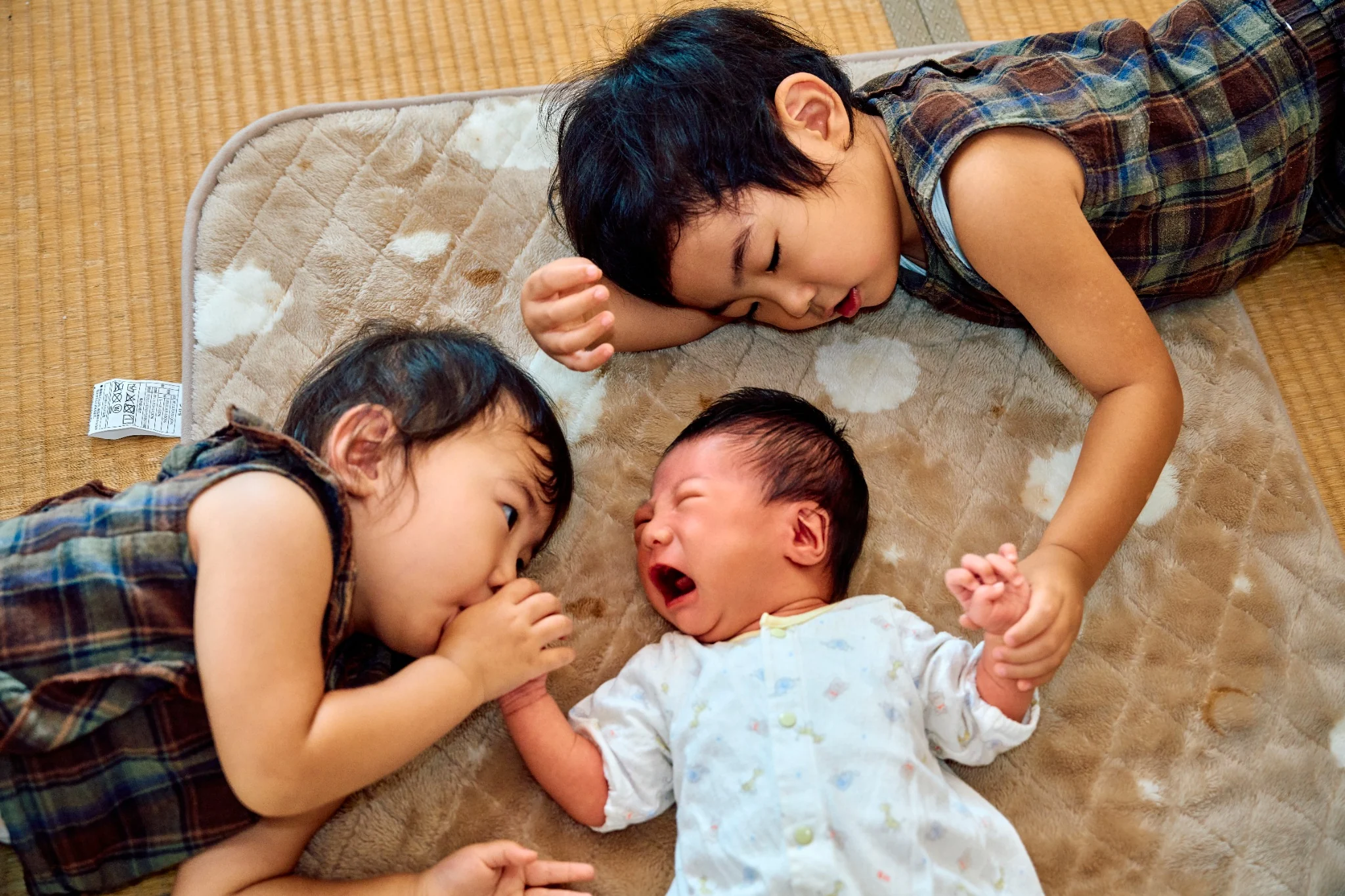 生まれたばかりの赤ちゃんを囲むきょうだいのニューボーンフォト